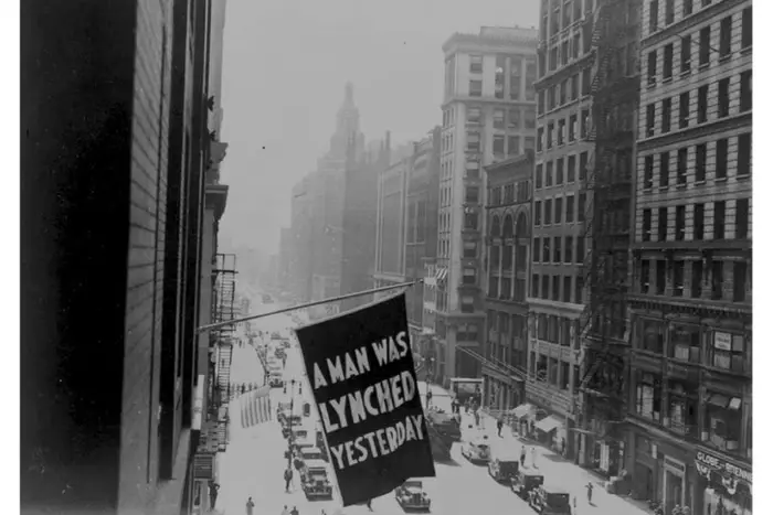 A 1920 photograph of Fifth Avenue from a building, with a sign that says "A MAN WAS LYNCHED YESTERDAY"